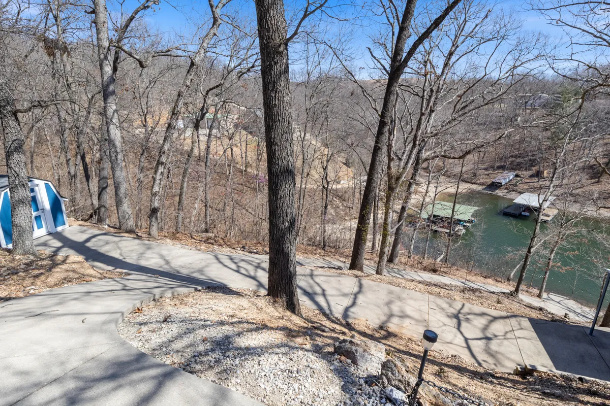 A view of a winding driveway framed by mature trees and a glimmering water view in the background. The landscape suggests a gateway to exploration and hints at the broader natural surroundings that guests can discover nearby.
