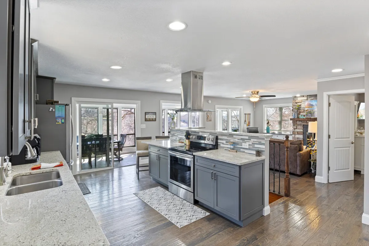 A bright, airy kitchen and living space with a large kitchen island, stainless steel appliances, and sliding glass doors that open to an inviting outdoor area. The layout is spacious and open, creating a seamless transition from the interior to the porch and beyond, with ample room for entertaining and family gatherings.