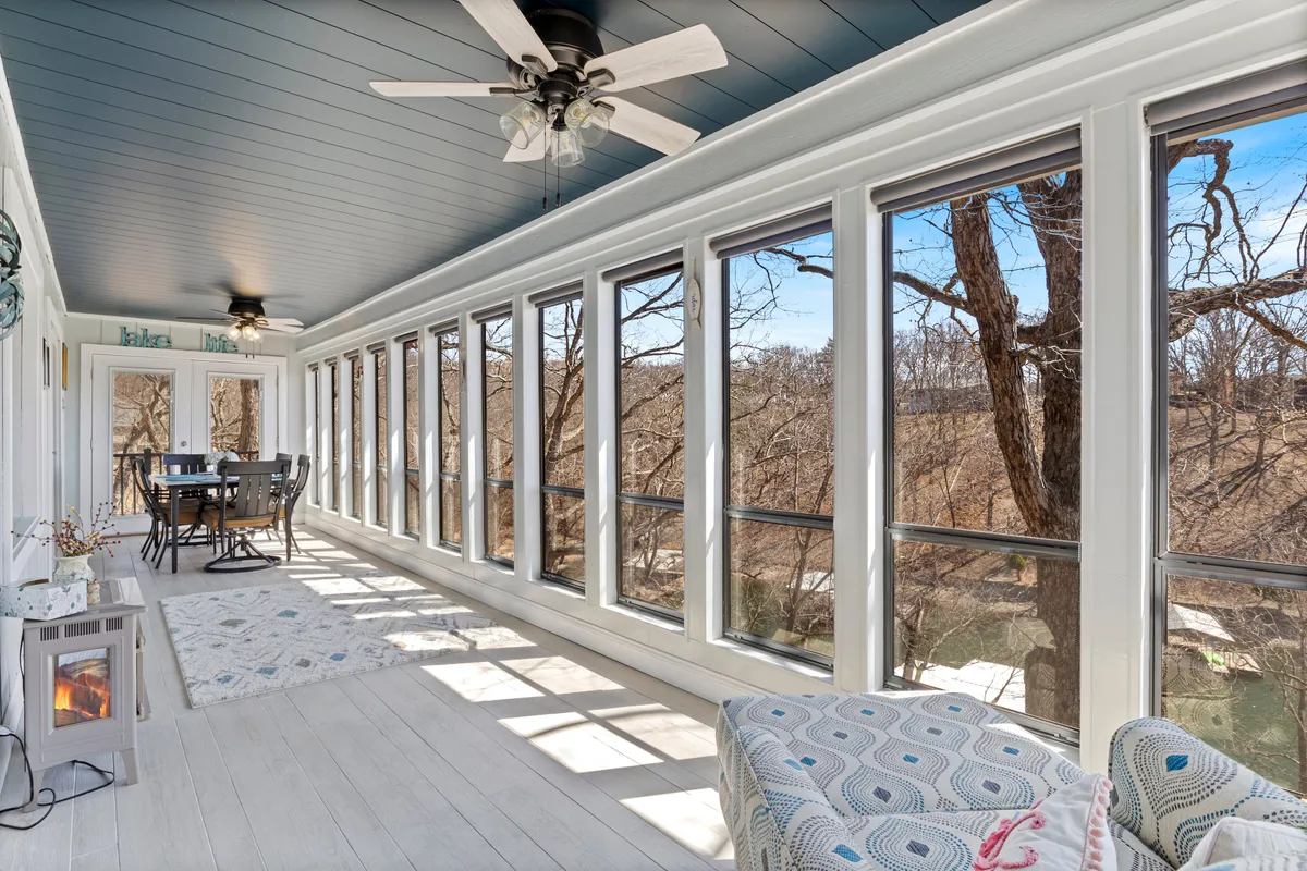 A welcoming dining space with a large window framing views of the outdoors, a family-sized dining table, comfortable seating, and a decorative lantern. The arrangement suggests casual dining or socializing while enjoying the natural scenery.