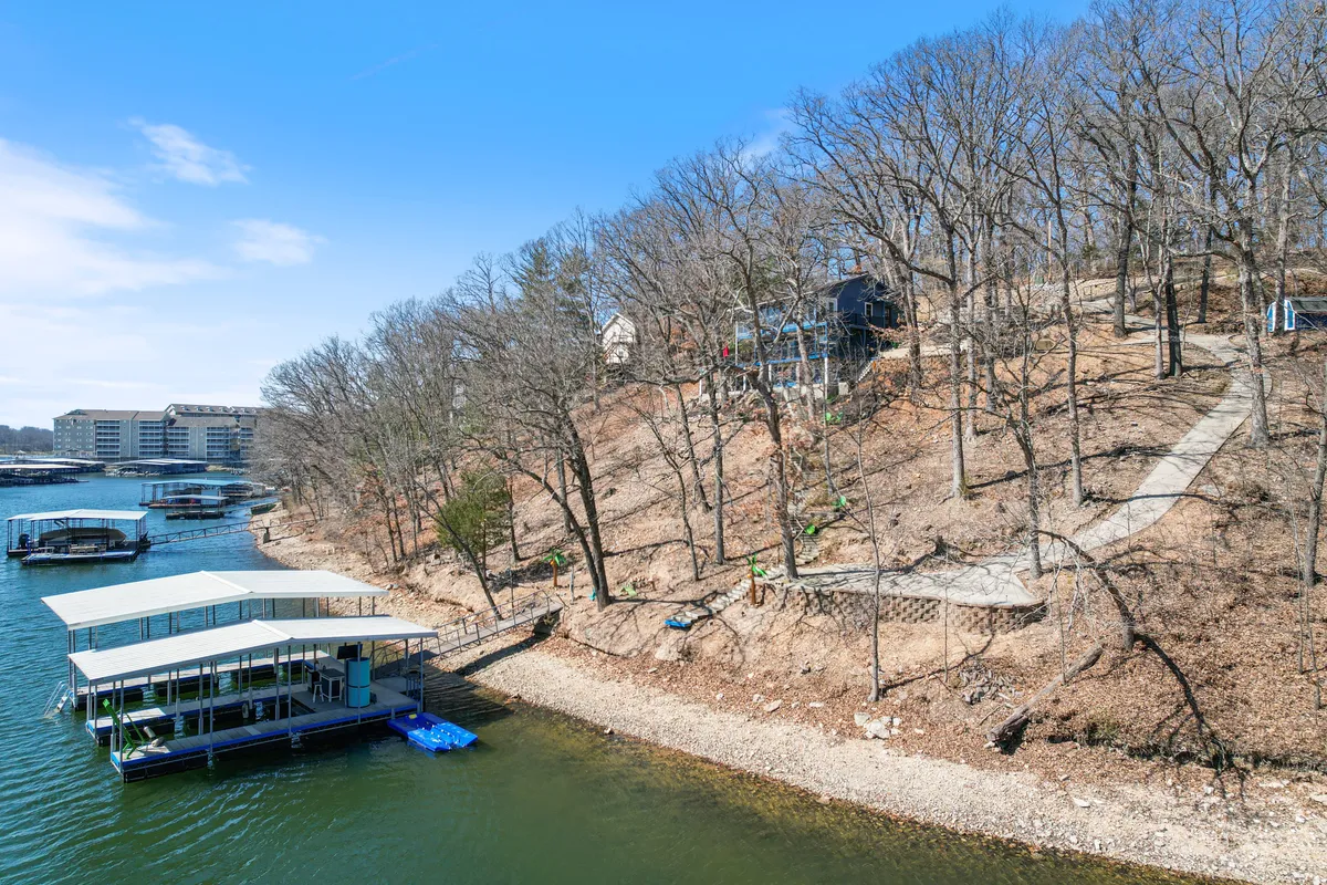 A serene lakeside scene with a dock, gentle hillside, and a scenic path winding through nature. The inviting water and surrounding landscape highlight opportunities for hiking, boating, and quiet contemplation by the water.